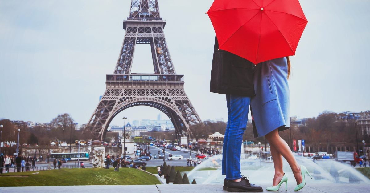 A couple kissing in front of the Eiffel Tower